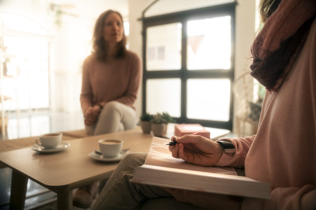 Frau im Hintergrund, unscharf, sitzt am Tisch und unterhält sich